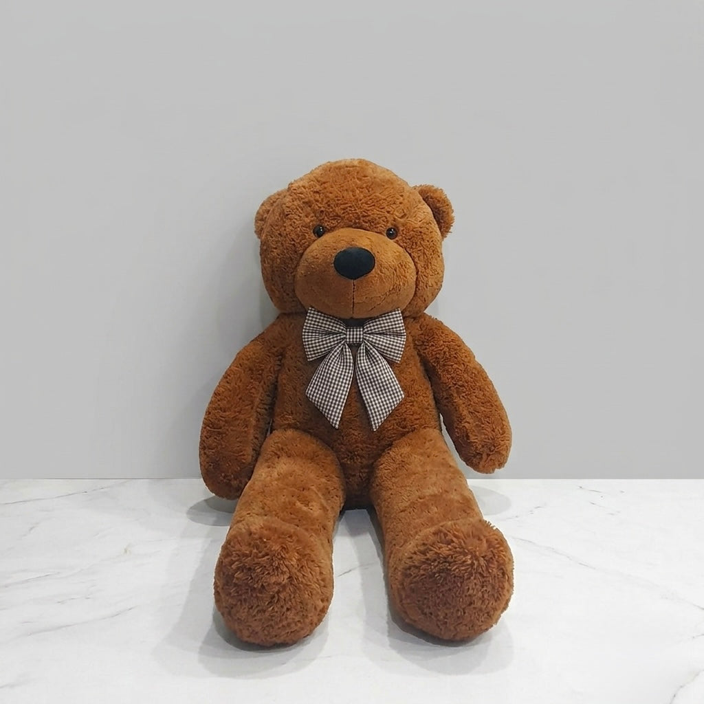 A brown plush teddy bear sitting on a white marble surface against a light gray wall, wearing a gray and white checkered bow tie.