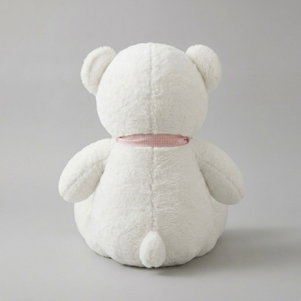A white plush teddy bear toy shown from the back, featuring soft textured fabric and a small pink ribbon tied around its neck, set against a neutral gray background.