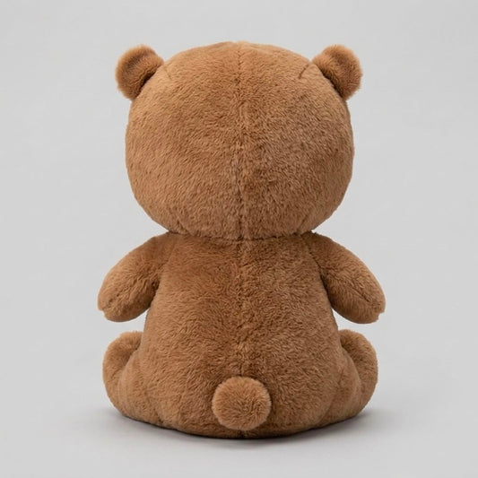 A brown plush teddy bear viewed from the back, sitting against a plain light gray studio background.