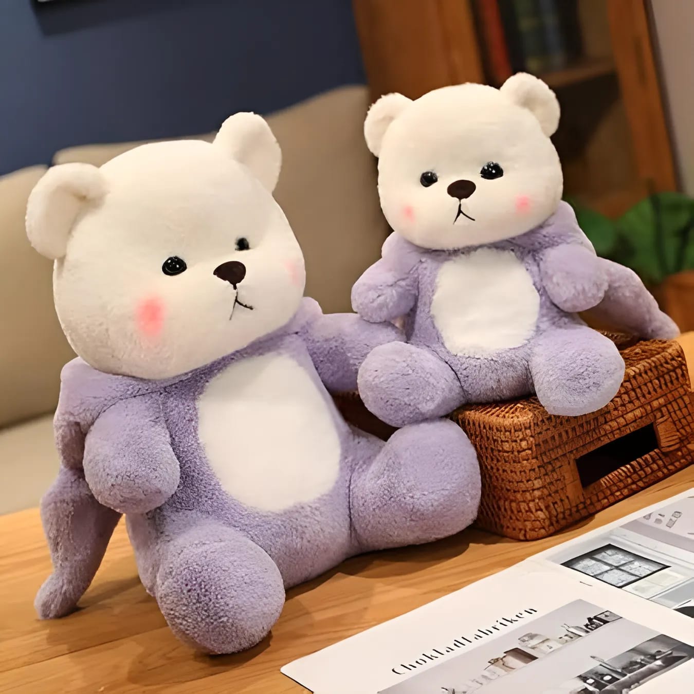 Two purple teddy bears sitting on a wooden surface with a magazine in the background.