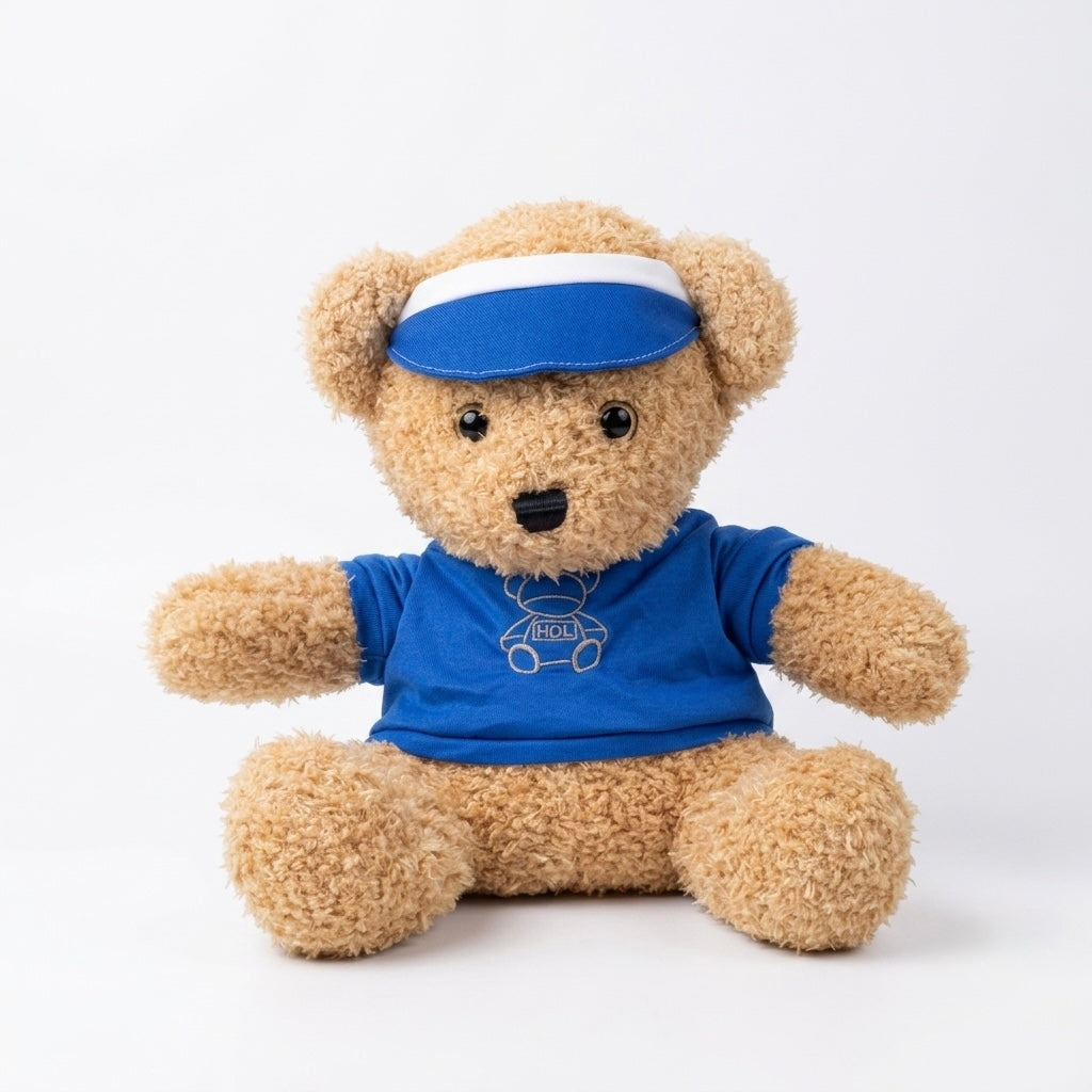 A plush teddy bear sitting against a plain white studio background, wearing a bright blue visor with a white stripe and a matching blue T-shirt with a small white car graphic.