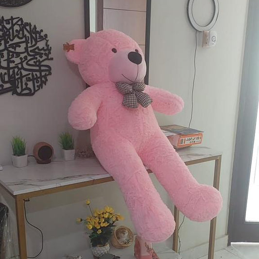 Pink teddy bear on a small table in a room with a mirror and decorative items.