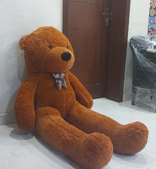 Brown teddy bear with a bow tie sitting on a white floor.