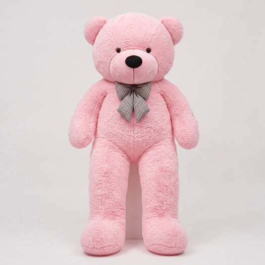 A large pink plush teddy bear standing upright against a plain light gray background, with a small gray patterned bow tie at the neck.