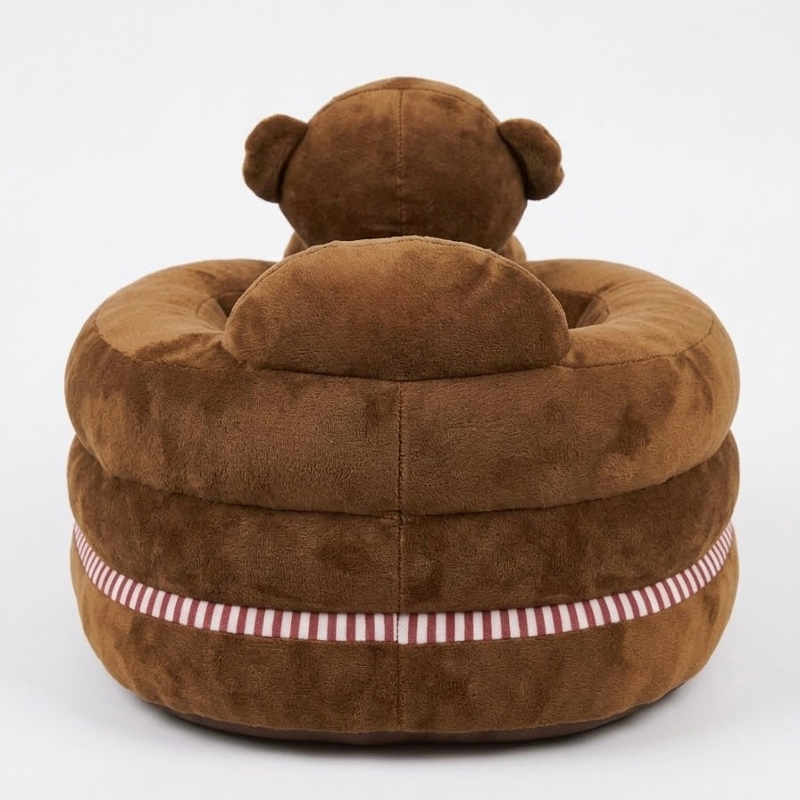 A plush brown teddy bear chair with a circular cushioned base and a small bear head on top, featuring a red and white striped band around the lower side, shown against a plain white background.