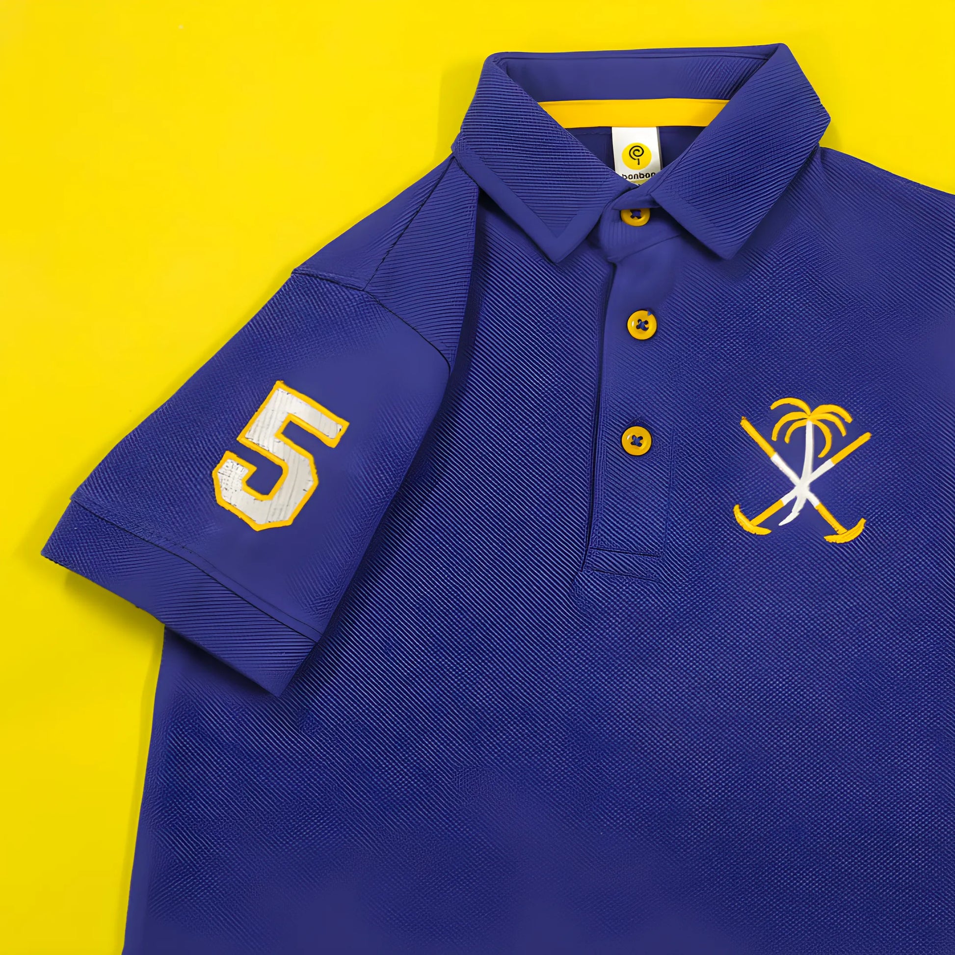 Blue polo shirt with number 5 and palm tree design on a yellow background