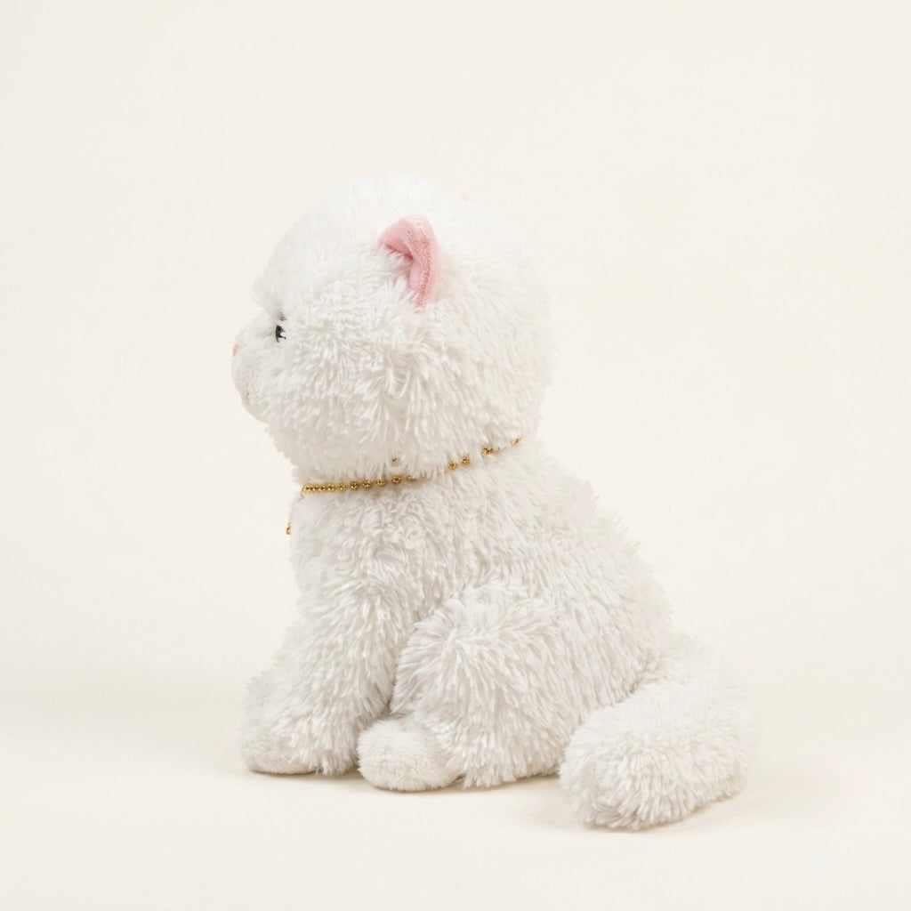 A white fluffy plush kitten toy sitting in profile on a warm off-white background, with a small pink inner ear and a thin gold collar.
