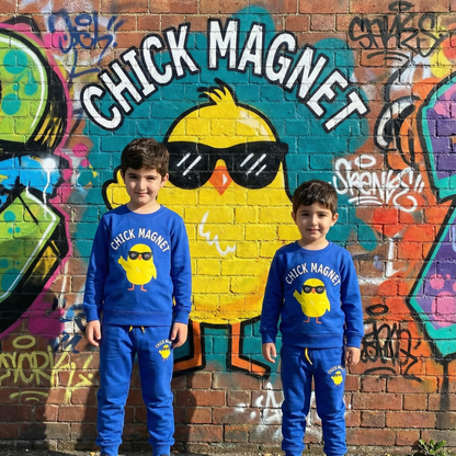 Two children wearing matching blue outfits with a chick graphic in front of a colorful mural.