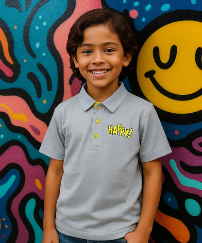 Child wearing a 'Happy!' shirt in front of a colorful wall with a smiley face.