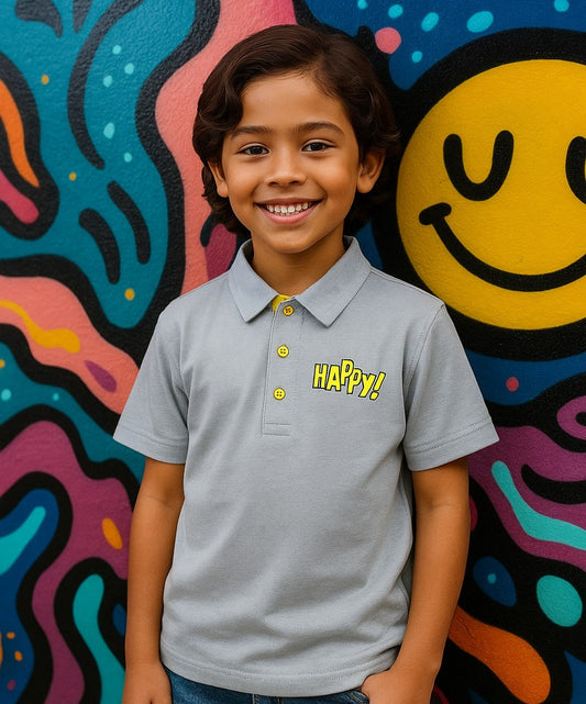 Child wearing a 'Happy!' shirt in front of a colorful wall with a smiley face.