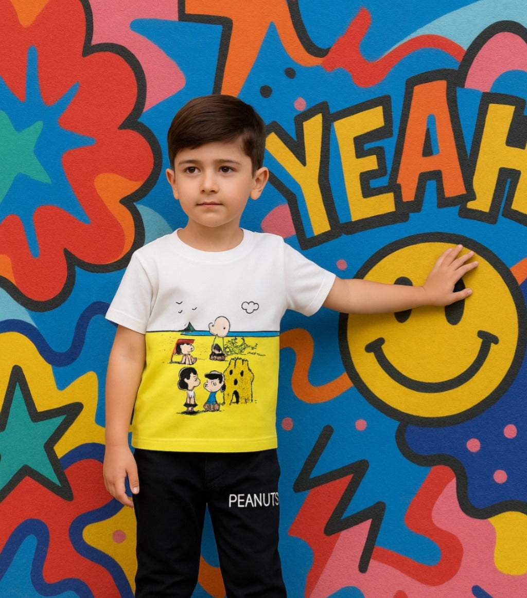 Child wearing a Peanuts-themed shirt in front of a colorful wall with graffiti-style text and smiley face.