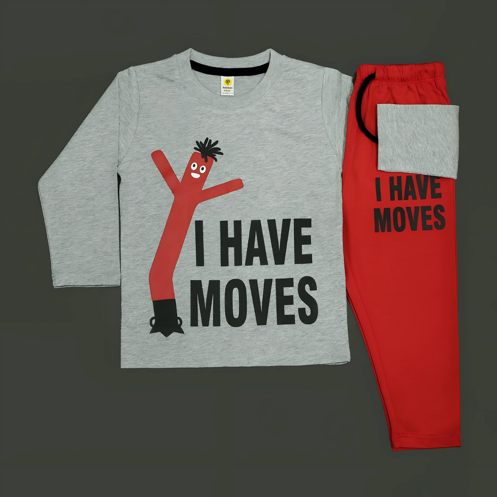 Children's outfit with gray shirt and red pants featuring 'I HAVE MOVES' text on a dark background