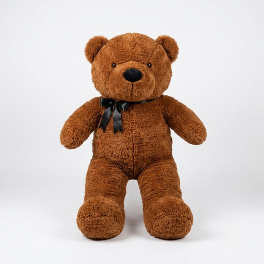 A brown plush teddy bear sitting upright against a light gray studio background, with a black satin bow tied around its neck.