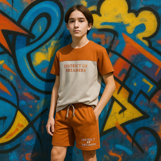 Person wearing a 'District of Dreamers' t-shirt and shorts in front of a colorful graffiti wall.
