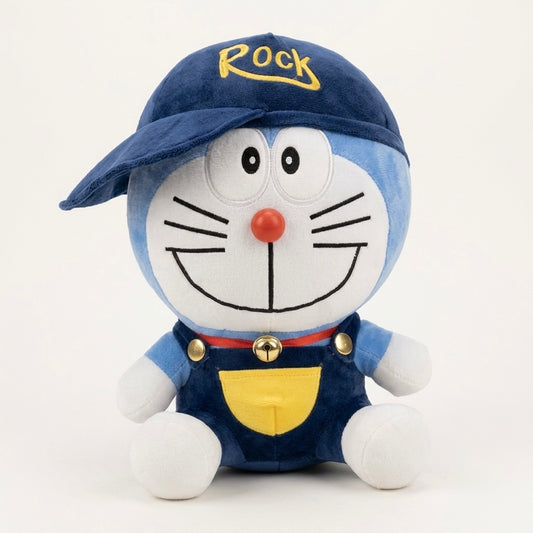 A plush toy of Doraemon wearing a blue cap with 'Rock' embroidered in yellow and blue overalls with a yellow pocket, on a white background.