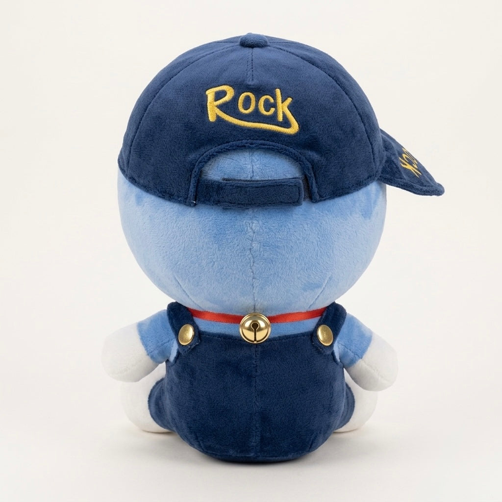 A plush toy of a blue character seen from the back, wearing a navy blue baseball cap with 'Rock' embroidered in yellow, dark blue overalls, a red collar with a gold bell, and white gloves, on a white background.
