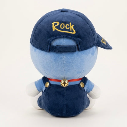 A plush toy of a blue character seen from the back, wearing a navy blue baseball cap with 'Rock' embroidered in yellow, dark blue overalls, a red collar with a gold bell, and white gloves, on a white background.