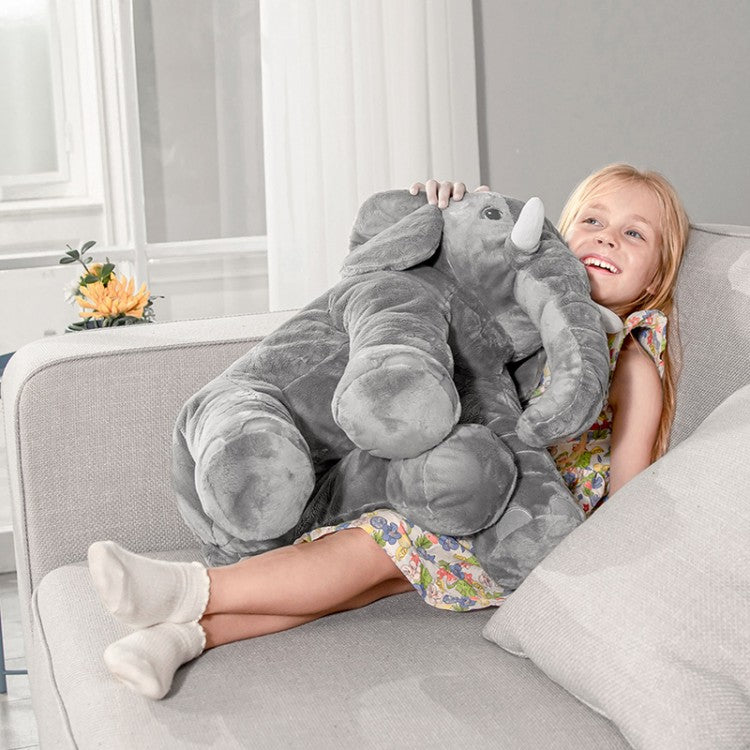 Child holding a large gray elephant plush toy on a couch