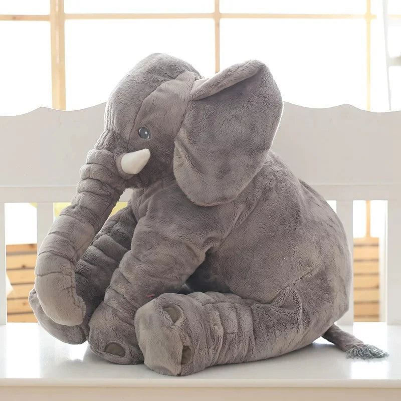 Plush elephant toy on a white surface with a light wooden background