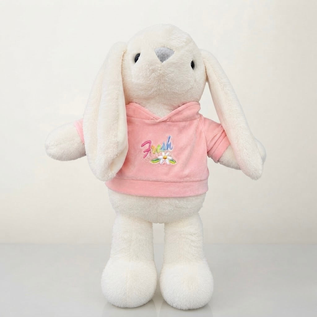 A plush white bunny toy wearing a pink hoodie with colorful embroidered text and a flower graphic on the chest, photographed against a plain light background.
