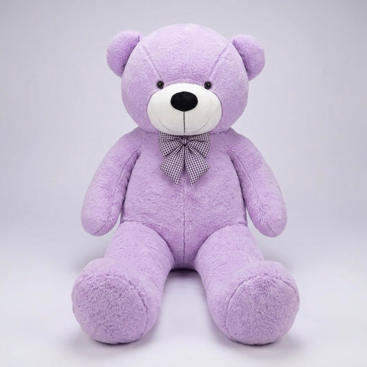 A plush purple teddy bear sitting upright against a light gray studio background. The bear has a white snout, small black eyes and nose, and a purple-and-white checkered bow tie.