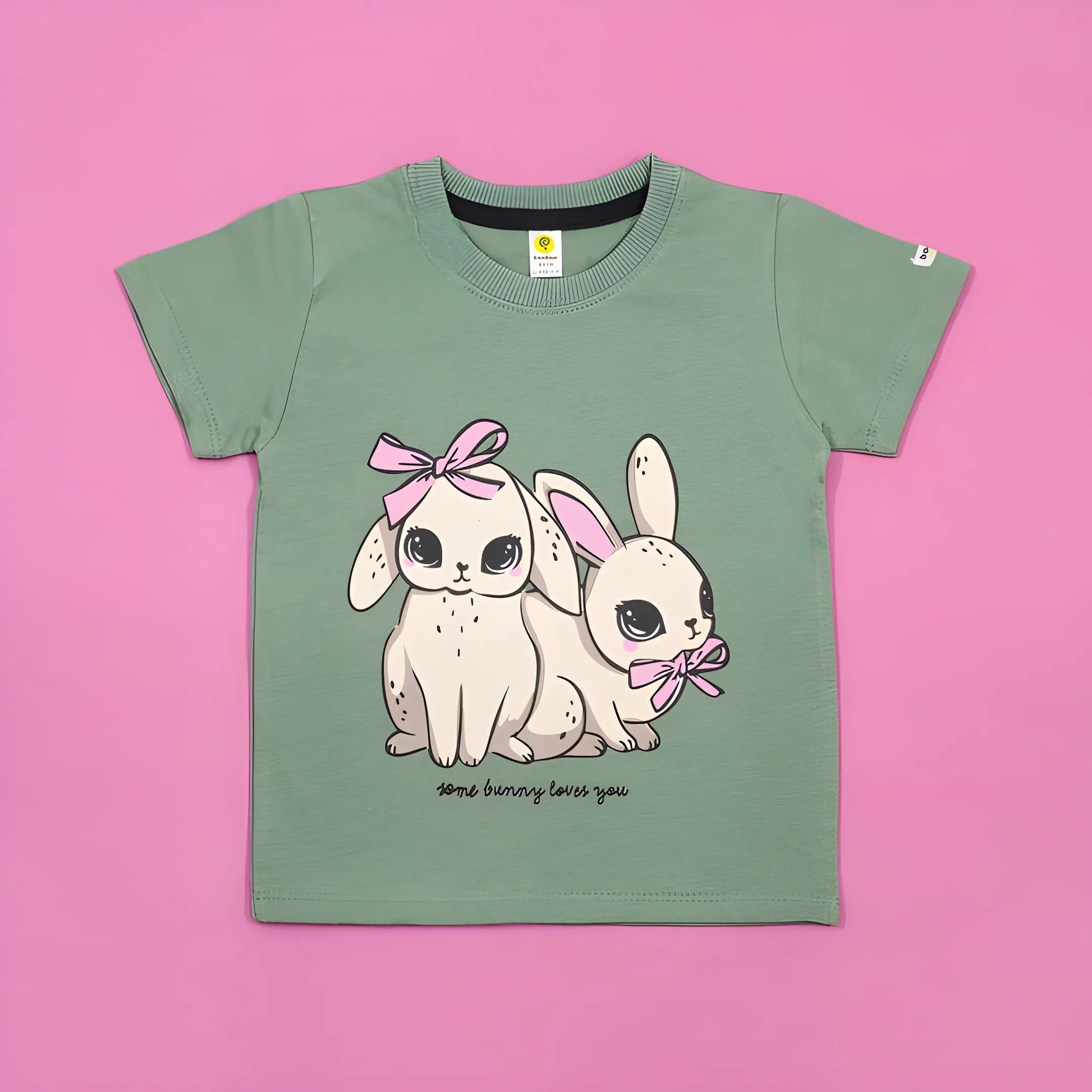 Green t-shirt with cartoon bunnies and text on a pink background