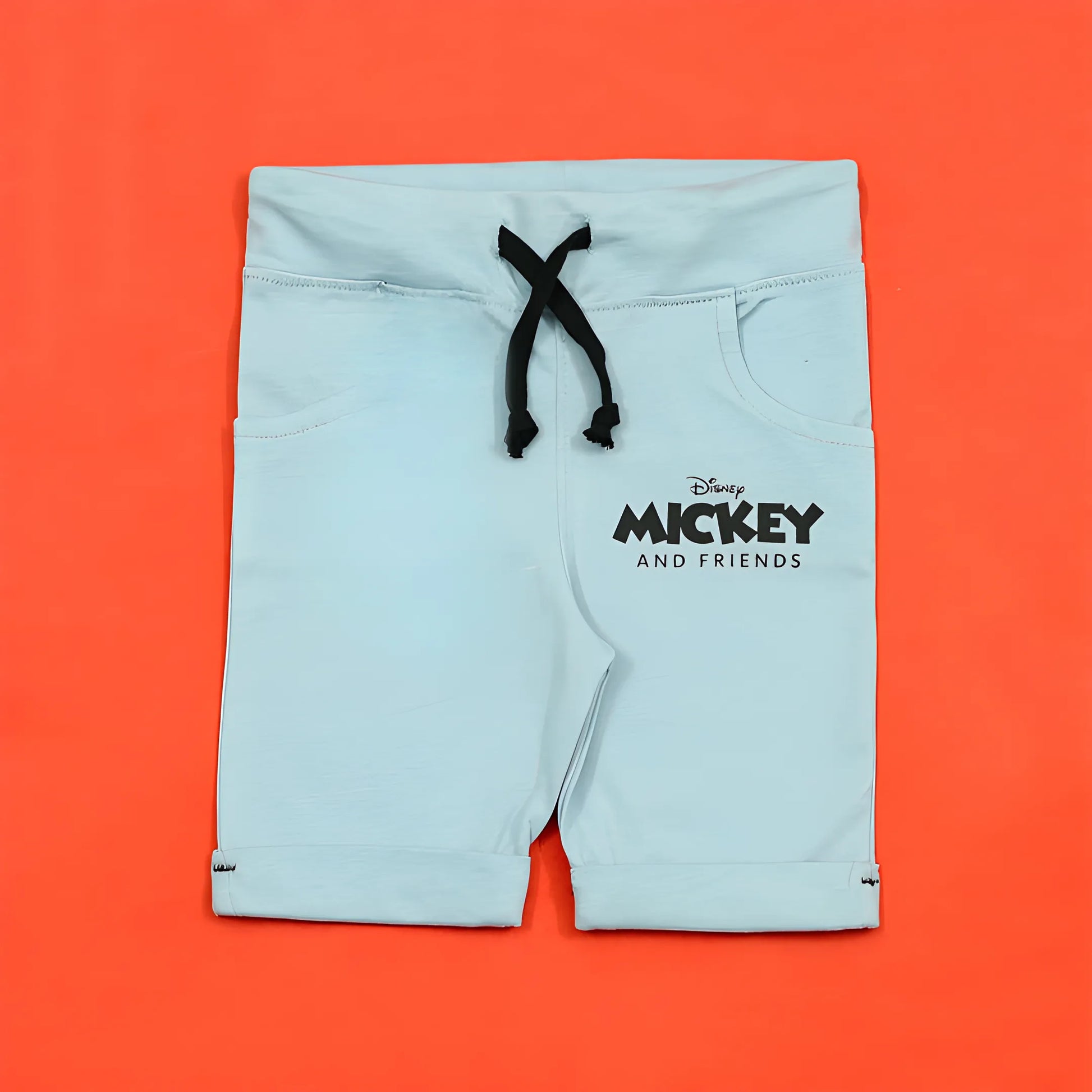 Light blue shorts with a black drawstring on an orange background, featuring Disney Mickey and Friends logo.