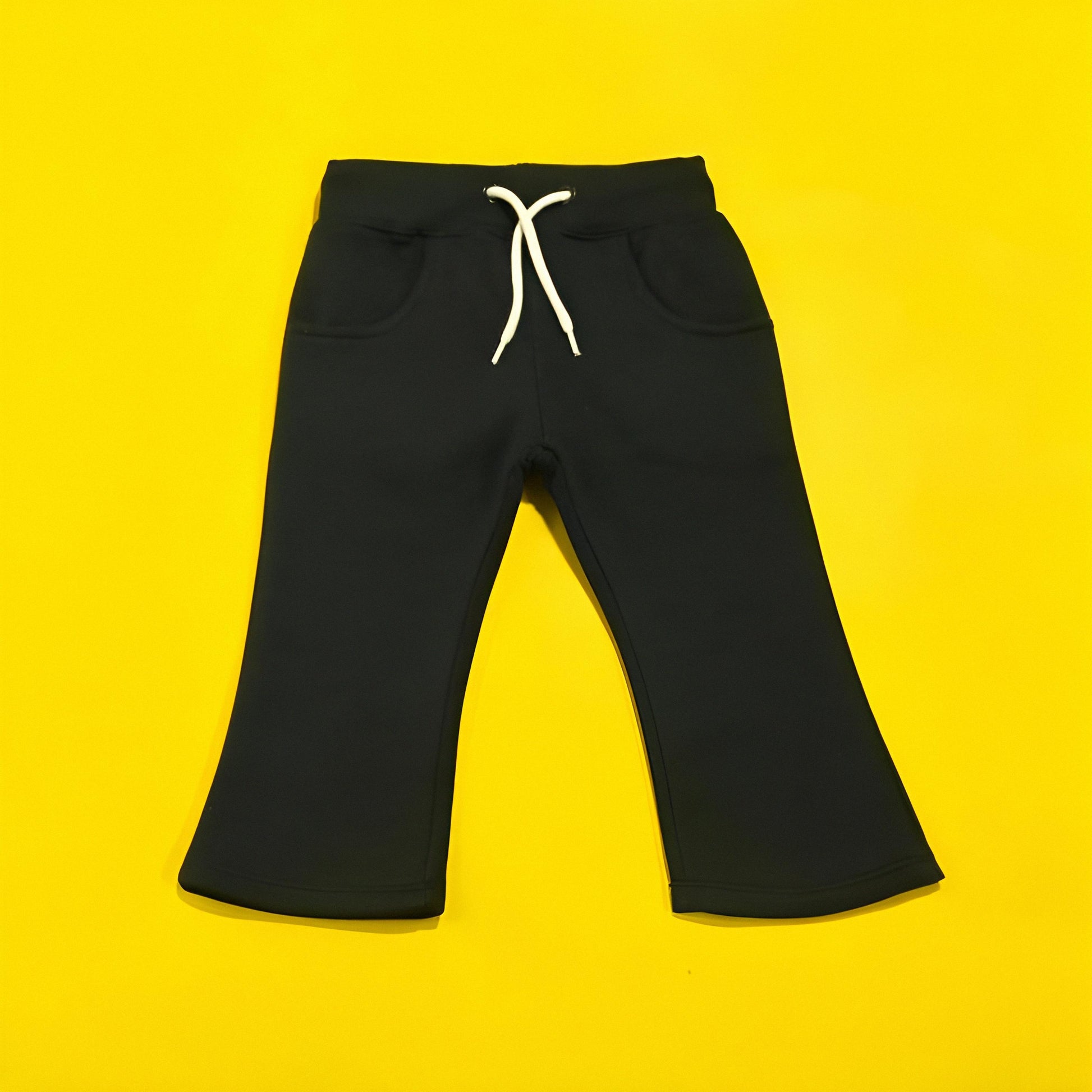 Black pants with a white drawstring on a yellow background