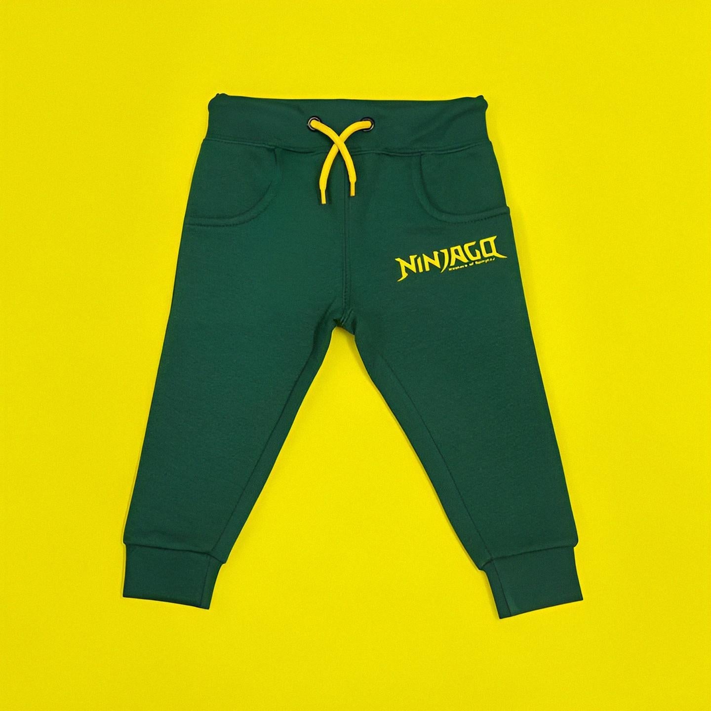 Green jogger pants with yellow drawstring and 'NINJAGO' logo on a yellow background