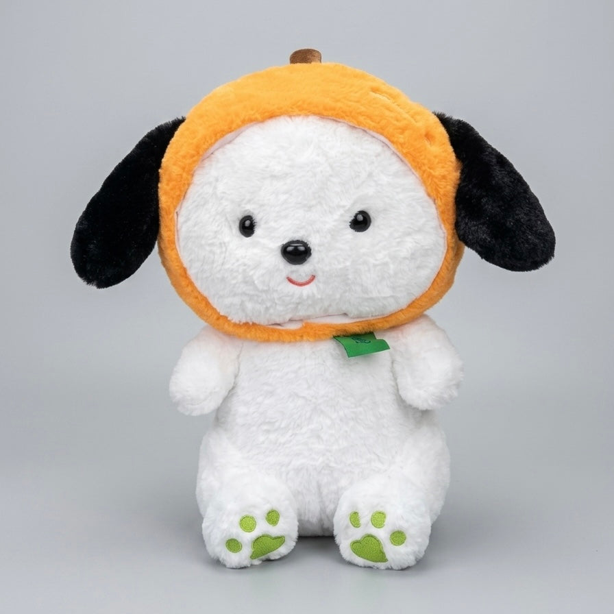 A white plush puppy toy wearing an orange pumpkin hat with black ears and a small green leaf accent, photographed against a light gray studio background.