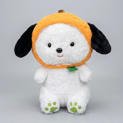 A white plush puppy toy wearing an orange pumpkin hat with black ears and a small green leaf accent, photographed against a light gray studio background.