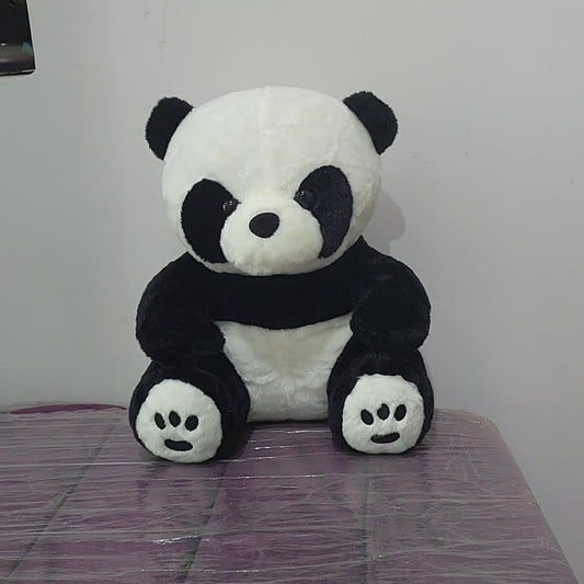 Plush panda toy on a purple surface with a white wall background