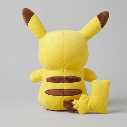 A yellow Pikachu plush toy shown from the back, sitting on a light gray studio background.