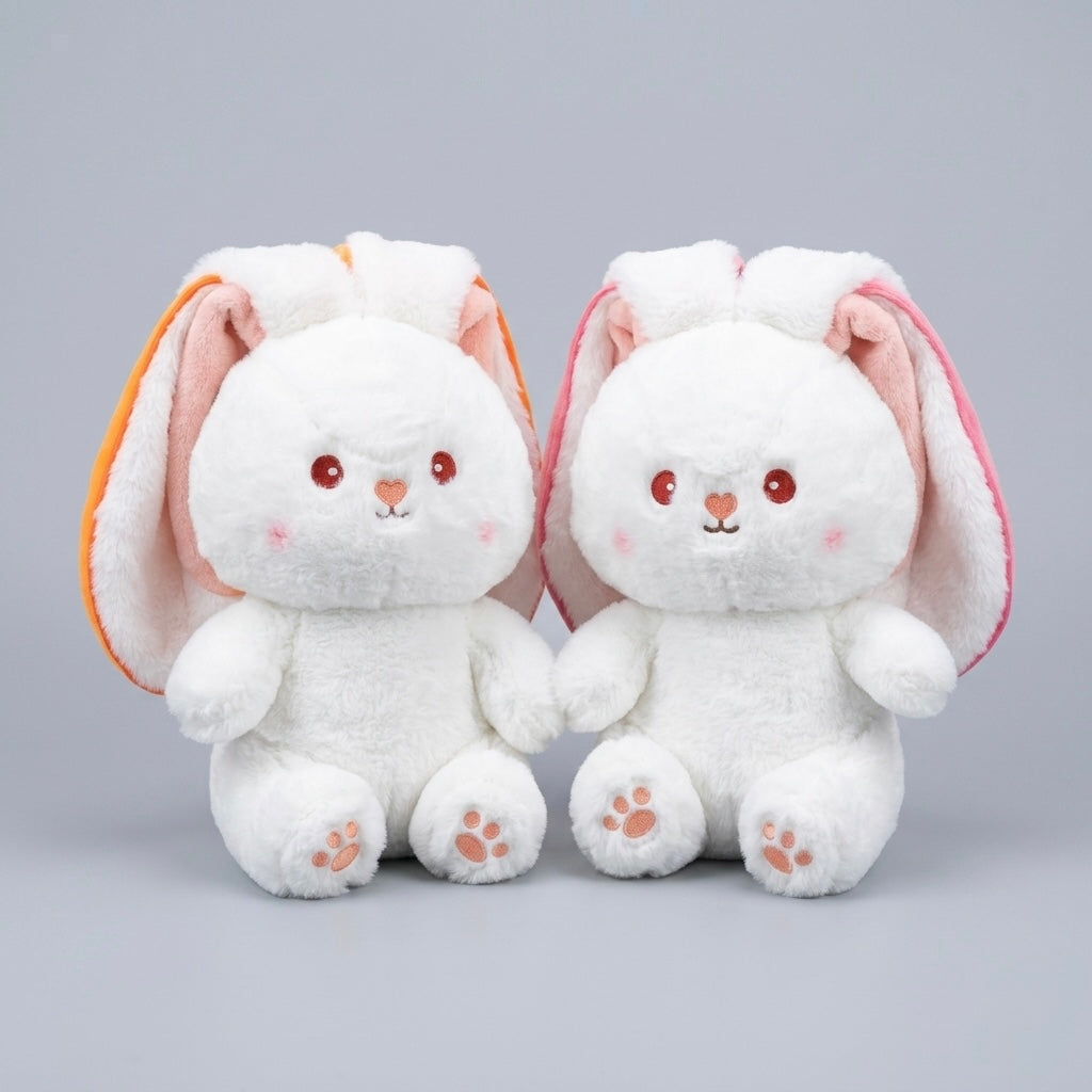 Two white plush bunny toys with long floppy ears, one featuring orange inner ears and the other pink inner ears, sitting side by side on a light gray background.