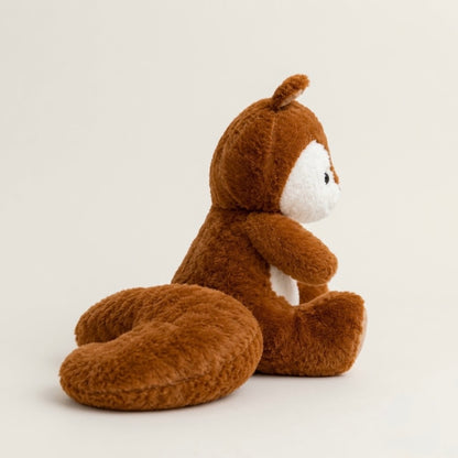 A plush brown squirrel toy with a white face and belly, sitting on a light beige background.