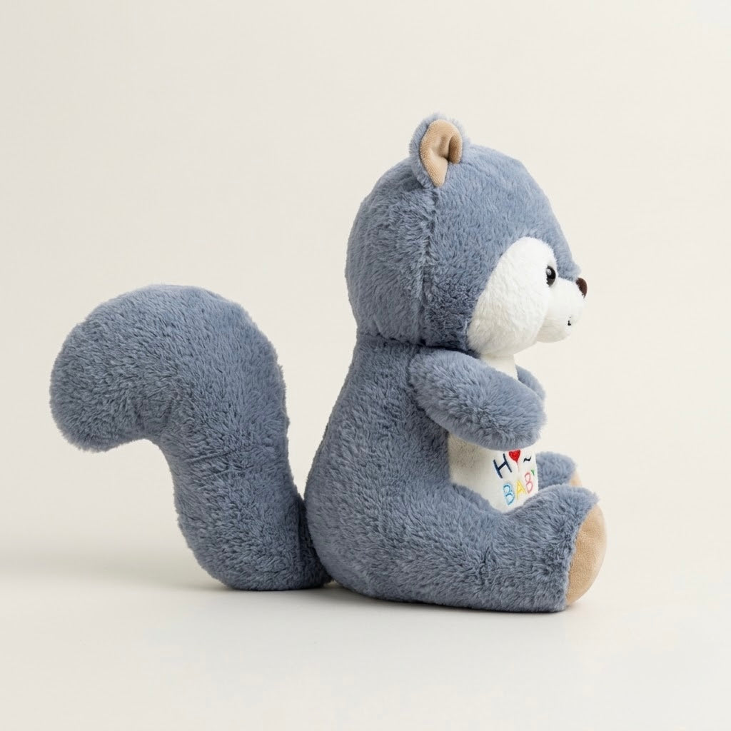 A plush toy squirrel in a dusty blue-gray color with a white face and belly, sitting and holding a small colorful heart-shaped card, photographed against a clean off-white background.