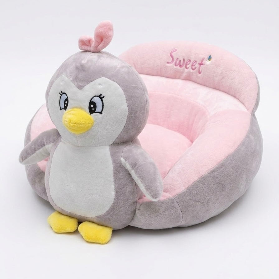 A plush penguin toy sitting inside a round pink pet bed with the word 'Sweet' embroidered on the back, photographed on a clean white background.